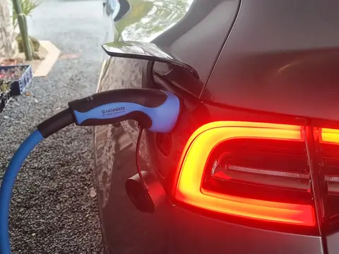 Voiture électrique en charge : la prise Type 2 du câble bleu branchée sur la voiture, à côté du feu arrière allumé