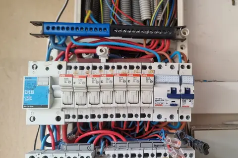 Tableau électrique ancien ouvert avec porte-fusibles, interrupteurs différentiels et disjoncteur