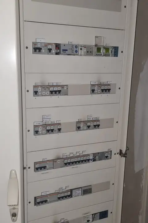 Armoire électrique ouverte avec des rangées de disjoncteurs étiquetés dans un local technique