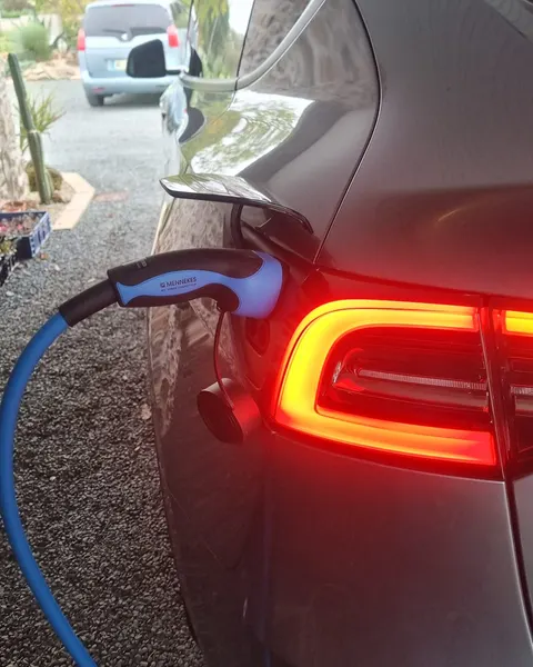 Voiture électrique grise en charge : la fiche Type 2 d’un câble bleu est branchée dans sa trappe, près du feu arrière allumé