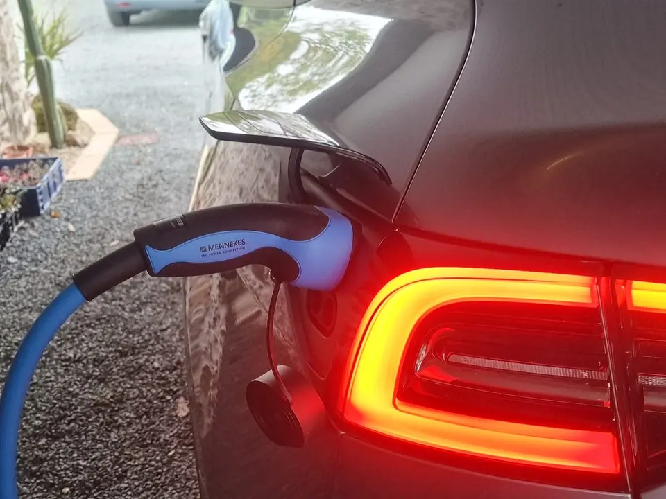Voiture électrique grise en charge : la fiche Type 2 d’un câble bleu est branchée dans sa trappe, près du feu arrière allumé