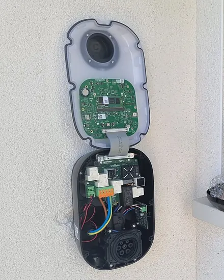 Borne Wallbox Pulsar ouverte pendant la pose sur une façade crépie blanche, outils posés sur le rebord de la fenêtre
