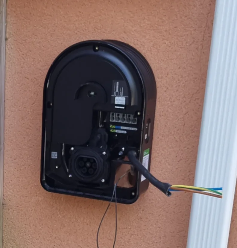 Avant : le socle noir d’une borne Schneider Charge fixé au mur, ouvert et câblé, fils en attente