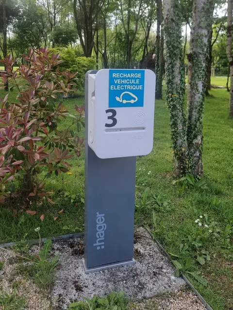Borne sur pied numérotée 3, fermée, logo Hager sur le fût, pelouse et arbres.