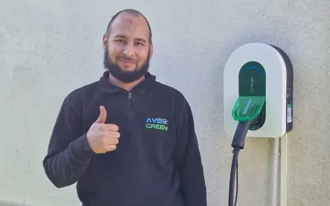Le dirigeant d’Ave Green, en sweat noir brodé AVE GREEN, pouce levé à côté d’une borne Schneider Charge.